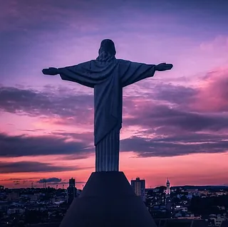 Statue von Jesus Christus mit ausgebreiteten Armen über einer Stadt.
