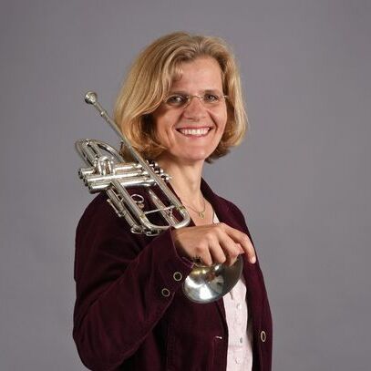 Porträt einer lächelnden Frau mit einer Trompete.