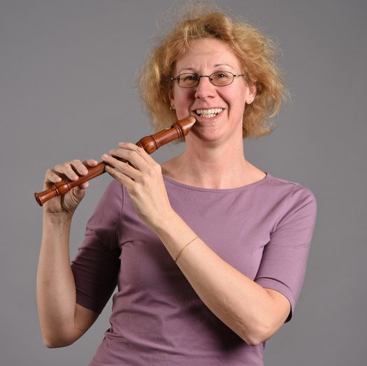 Porträt einer lächelnden Frau mit einer Blockflöte.